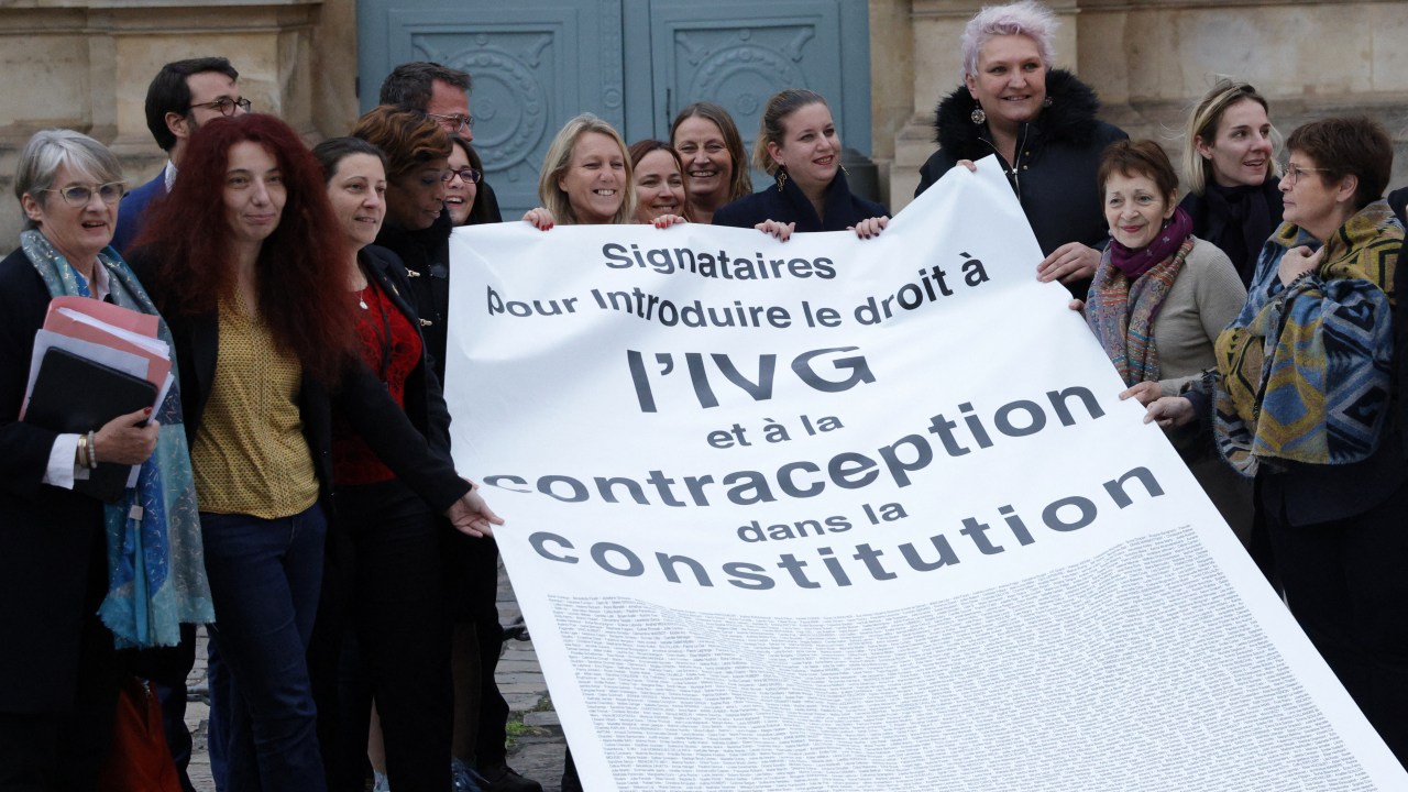Members of Parliament of French leftist party La France Insoumise (LFI) and members of pro-abortion associations celebrate with a banner after the parliament voted to add the right to abortion to the constitution, outside The National Assembly in Paris on November 24, 2022. (Photo by Geoffroy Van der Hasselt / AFP)