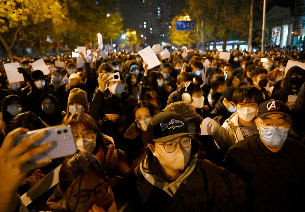Protesters march along a street during a rally for the victims of a deadly fire as well as a protest against China's harsh Covid-19 restrictions in Beijing on November 28, 2022. - A deadly fire on November 24, 2022 in Urumqi, the capital of northwest China's Xinjiang region, has become a fresh catalyst for public anger, with many blaming Covid lockdowns for hampering rescue efforts, as hundreds of people took to the streets in China's major cities on November 27, 2022 to protest against the country's zero-Covid policy in a rare outpouring of public anger against the state. Authorities deny the claims. (Photo by Noel CELIS / AFP)