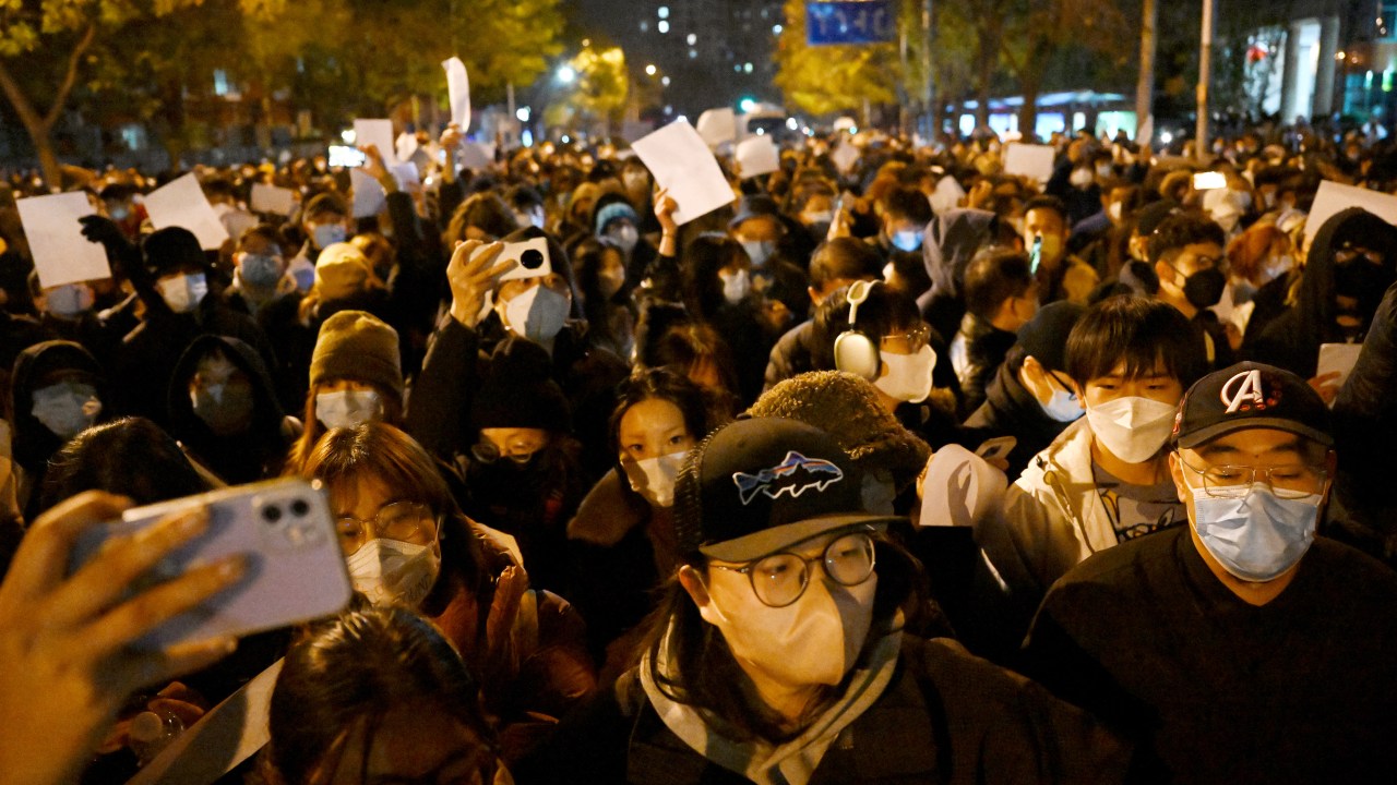 Protesters march along a street during a rally for the victims of a deadly fire as well as a protest against China's harsh Covid-19 restrictions in Beijing on November 28, 2022. - A deadly fire on November 24, 2022 in Urumqi, the capital of northwest China's Xinjiang region, has become a fresh catalyst for public anger, with many blaming Covid lockdowns for hampering rescue efforts, as hundreds of people took to the streets in China's major cities on November 27, 2022 to protest against the country's zero-Covid policy in a rare outpouring of public anger against the state. Authorities deny the claims. (Photo by Noel CELIS / AFP)