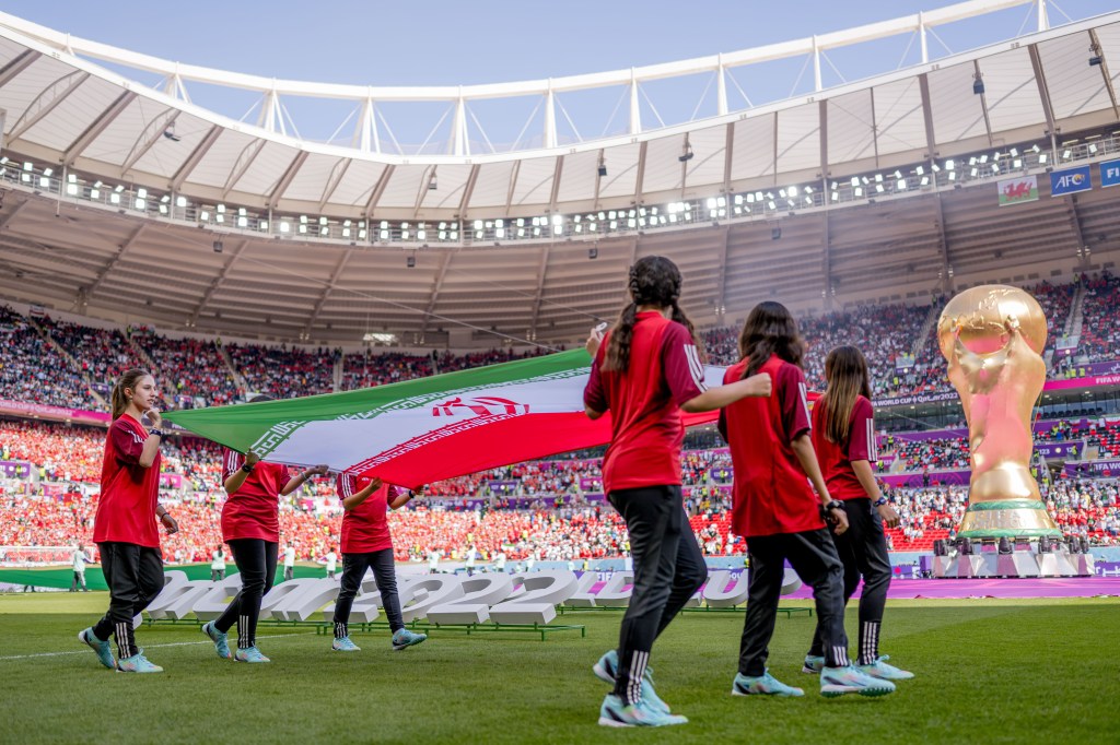 DOHA, QATAR - 25 DE NOVEMBRO: Meninas carregam a bandeira do Irã no estádio durante a partida do Grupo B da Copa do Mundo da FIFA Qatar 2022 entre País de Gales e Irã no Estádio Ahmad Bin Ali em 25 de novembro de 2022 em Doha, Qatar