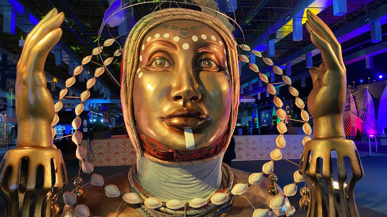 Escultura de uma figura feminina dourada que representa a logo da Segunda Expo Internacional da Consciência Negra