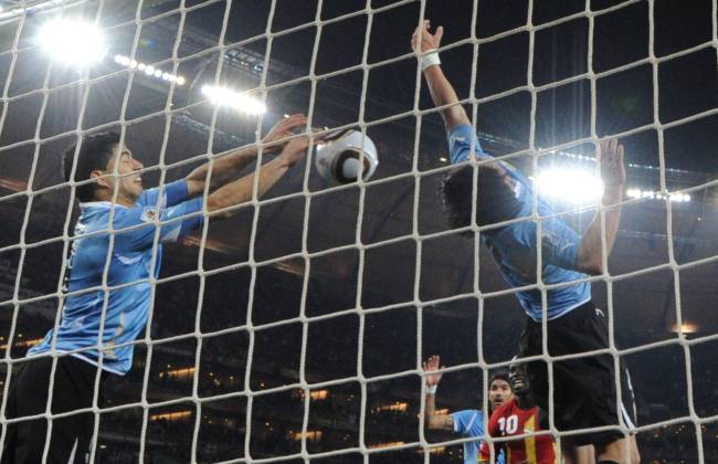 FILES-FBL-WC2010-MATCH58-URU-GHA (FILES) In this file photo taken on July 2, 2010 Uruguay's striker Luis Suarez (L) stops the ball with the hand leading to a red card and a penalty for Ghana during the extra-time of 2010 World Cup quarter-final match Uruguay vs Ghana on July 2, 2010 at Soccer City stadium in Soweto, suburban Johannesburg. - Ghana say they have no plans to take revenge on Uruguay and Luis Suarez when they meet them on December 2, 2022 in the final matchday of World Cup Group H as they seek a place in the last 16. On 2 July 2010, Soccer City Stadium in Johannesburg hosted the quarter-final, which became one of the most dramatic and emotional World Cup matches of the 21st century. With the score at 1-1 at the end of the ninety minutes, there was nothing to suggest that the score would change in extra time. Then, in the 119th minute, came the most memorable play of South Africa 2010. Ghana had a free kick; the goalkeeper Fernado Muslera failed to take it and an African player headed and when the ball was going in, Luis Suarez, like a volleyball player, parried the ball with both hands and prevented the Celeste goal from falling. (Photo by ROBERTO SCHMIDT / AFP)