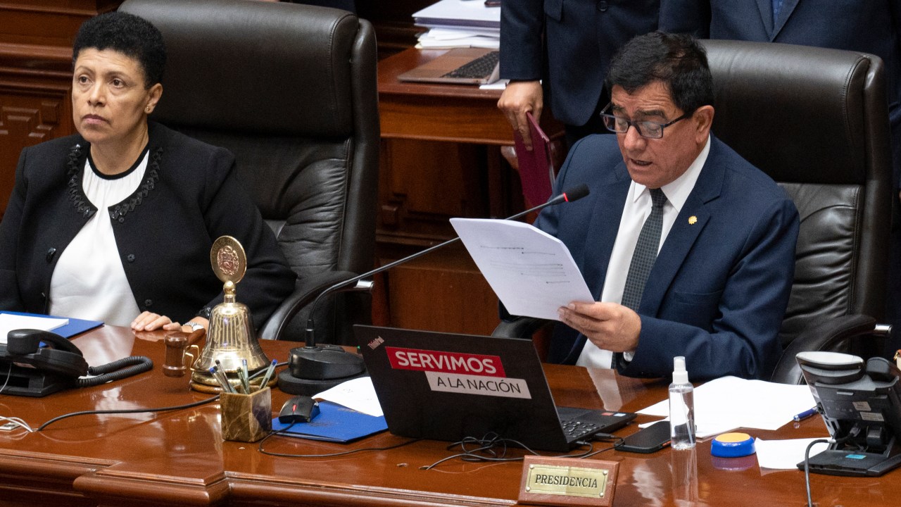 President of the Peruvian Congress Jose Williams Zapata (R) reads the vote result to impeach President Pedro Castillo during the plenary session in Lima on December 7, 2022. - Peru's President Pedro Castillo dissolved Congress on December 7, 2022, announced a curfew and said he will form an emergency government that will rule by decree, just hours before the legislature was due to debate a motion of impeachment against him. (Photo by Cris BOURONCLE / AFP)