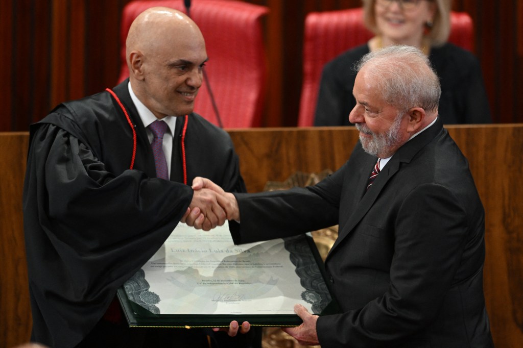 Brazil's President-elect Luiz Inacio da Silva (R) receives from the President of the Superior Electoral Court (TSE) Alexandre de Moraes (L) the certification diploma during a ceremony at the TSE headquarters in Brasilia, December 12, 2022. - Luiz Inacio Lula da Silva received this Monday the "diploma" of President-elect from the highest electoral authority in Brazil, which formalizes his path to take office on January 1, 2023. (Photo by EVARISTO SA / AFP)