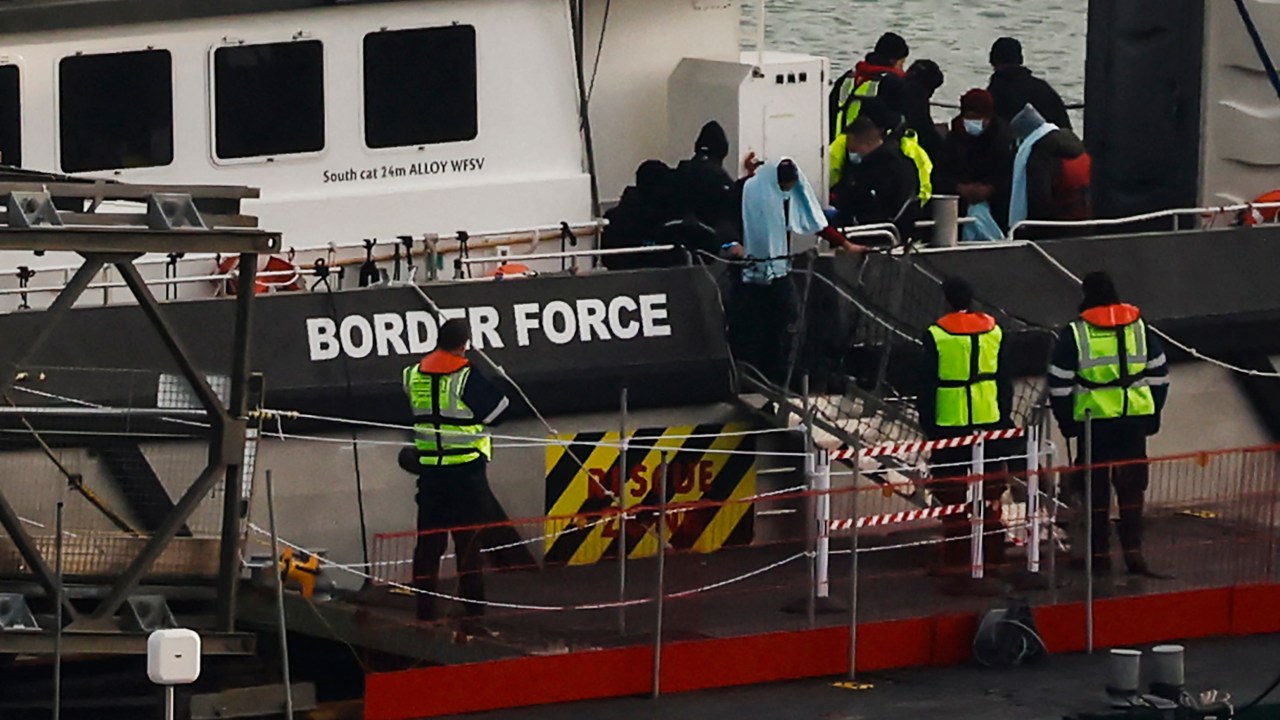 Migrants picked up at sea while attempting to cross the English Channel, are escorted off from a UK Border Force boat upon arrival at the Marina in Dover, southeast England, on December 14, 2022. - At least four people died when a small boat apparently packed with migrants capsized in freezing temperatures in the Channel overnight, the UK government said on December 14, 2022. The UK Maritime and Coastguard Agency (MCA) coordinated the rescue operation, which also involved Border Force, police and other emergency responders. Lifeboats were launched from the Channel port of Dover at 3:07 am British time (0307 GMT), followed by vessels from Ramsgate and Hastings along the coast, it added. (Photo by CARLOS JASSO / AFP)