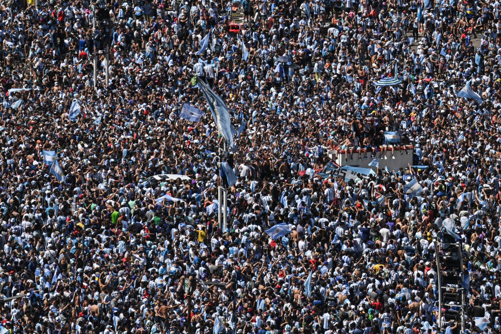 Fans of Argentina wait for the bus with Argentina's players to pass through the Obelisk to celebrate after winning the Qatar 2022 World Cup tournament in Buenos Aires on December 20, 2022. - The airplane transporting World Cup winners Argentina and their captain Lionel Messi back from Qatar arrived at the Ezeiza international airport in Buenos Aires at 2:40 am (0540 GMT) on Tuesday. On midday Tuesday they will begin a tour through the Buenos Aires city center with millions expected out in the streets on what is a public holiday. (Photo by Luis ROBAYO / AFP)