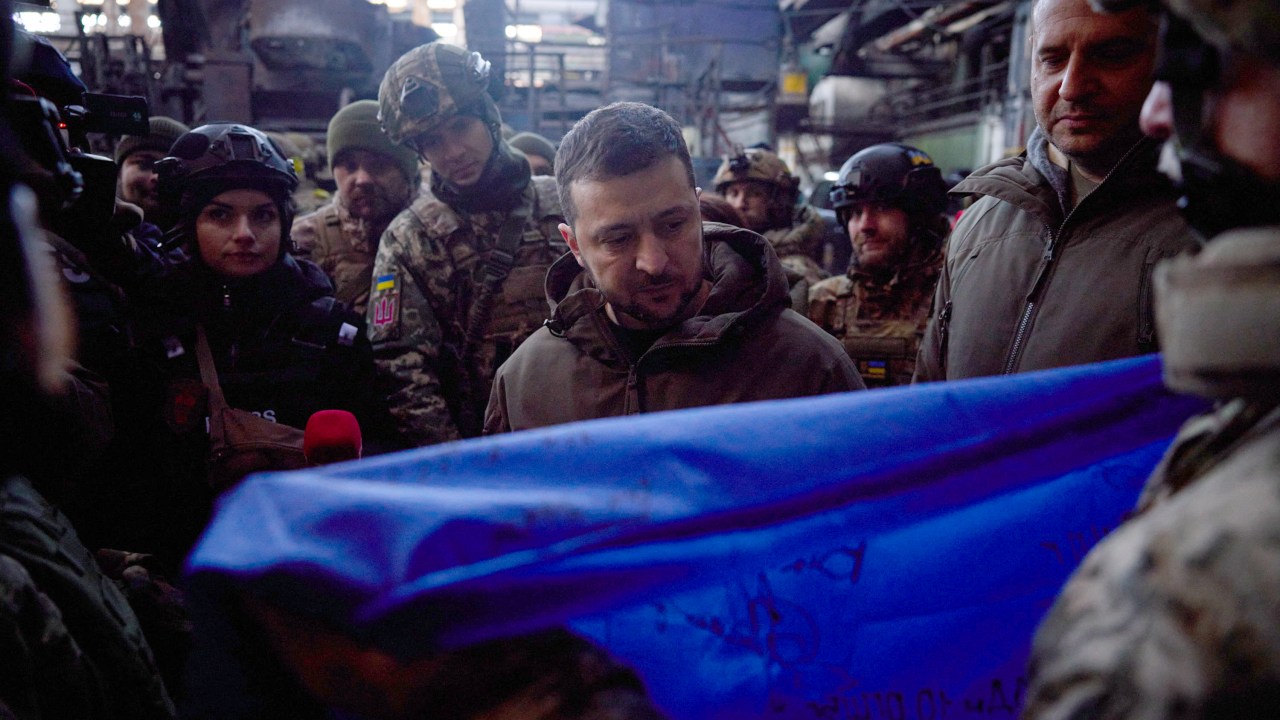 This handout picture taken and released by the Ukrainian Presidential press service on December 20, 2022, shows Ukrainian President Volodymyr Zelensky receiving a Ukrainian flag from Bakhmut defenders with their signatures during his visit to the frontline town of Bakhmut, Donetsk region, amid the Russian invasion of Ukrtaine. (Photo by STRINGER / UKRAINIAN PRESIDENTIAL PRESS SERVICE / AFP) / RESTRICTED TO EDITORIAL USE - MANDATORY CREDIT "AFP PHOTO / Ukrainian Presidential press service " - NO MARKETING NO ADVERTISING CAMPAIGNS - DISTRIBUTED AS A SERVICE TO CLIENTS