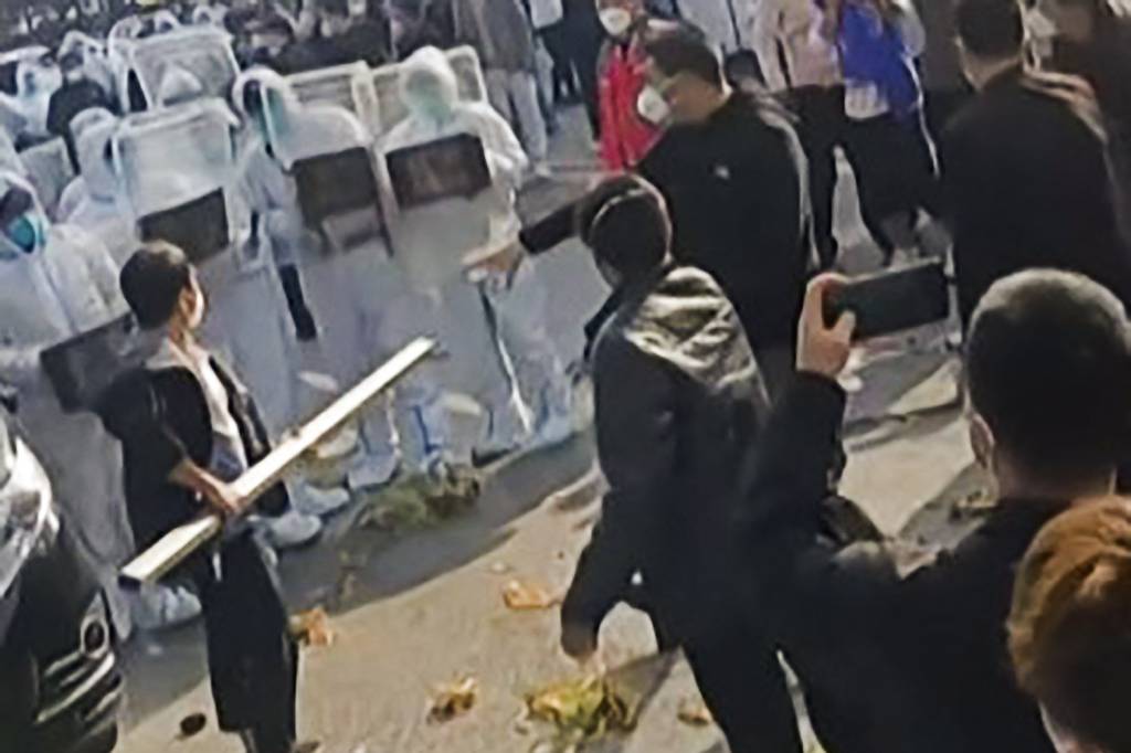 ABRE-FOXCONNIS-IPHONE-PROTESTOS-COVID-2022-01.jpg REBELIÃO - Operários da Foxconn enfrentam a polícia (em traje de proteção): briga por salário extra nas quarentenas -