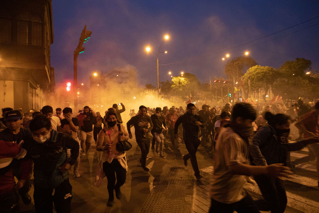 11 December 2022, Peru, Lima: People flee tear gas used by police amid protests. After the impeachment of the president in Peru, there were protests in several cities, including the capital Lima Photo: Lucas Aguayo Araos/dpa (Photo by Lucas Aguayo Araos/picture alliance via Getty Images)