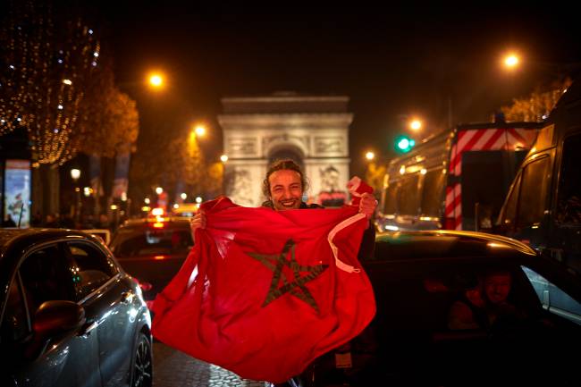 PARIS, FRANCE - DECEMBER 10: Morocco Fans celebrate on the Champs Elysees after their team's 1-0 victory over Portugal to reach the semi-finals of the Fifa World Cup on December 10, 2022 in Paris, France. Morocco's victory marks the first time an African nation has qualified for the semi-finals of a FIFA World Cup. (Photo by Kiran Ridley/Getty Images)