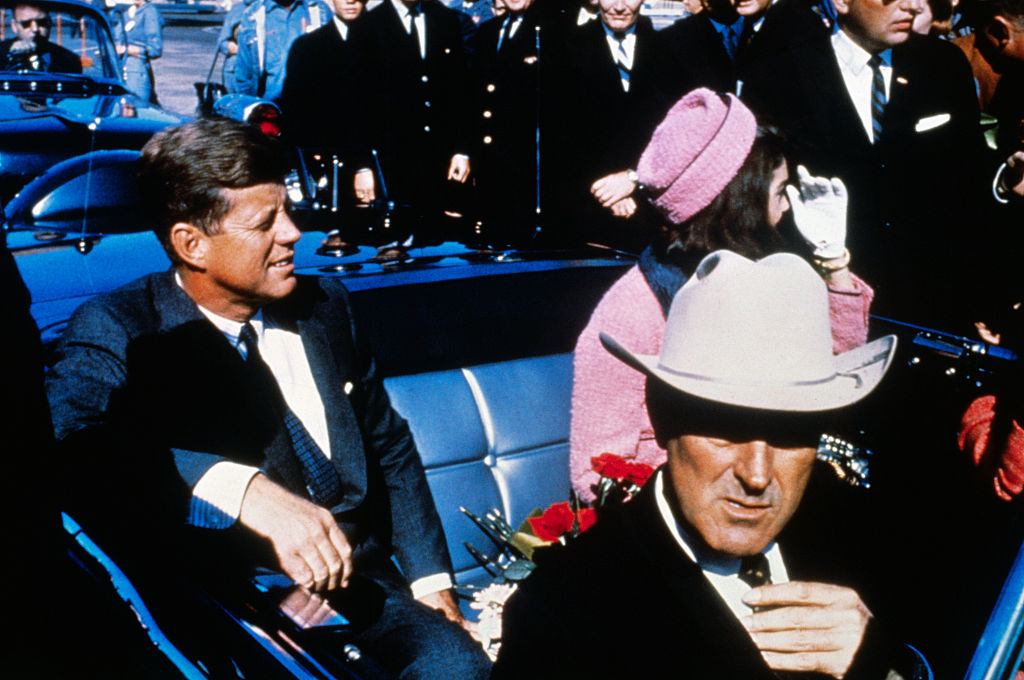 US President John F Kennedy (left), First Lady Jacqueline Kennedy (in pink), and Texas Governor John Connally ride in a motorcade from the Dallas airport into the city.