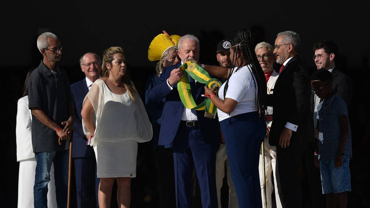 Brazil's new President Luiz Inacio Lula da Silva receives the presidential sash from indigenous Brazilian leader and environmentalist Raoni Metuktire, known as Chief Raoni (back), and other community representatives, at Planalto Palace after his inauguration ceremony at the National Congress, in Brasilia, on January 1, 2023. - Lula da Silva, a 77-year-old leftist who already served as president of Brazil from 2003 to 2010, takes office for the third time with a grand inauguration in Brasilia. (Photo by CARL DE SOUZA / AFP)