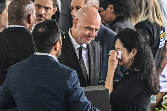 FIFA President Gianni Infantino (C) greets the wife of Brazilian football legend Pele, Marcia Aoki (R), during his wake at the Urbano Caldeira stadium in Santos, Sao Paulo, Brazil on January 2, 2023. - Brazilians bid a final farewell this week to football giant Pele, starting Monday with a 24-hour public wake at the stadium of his long-time team, Santos. (Photo by NELSON ALMEIDA / AFP)