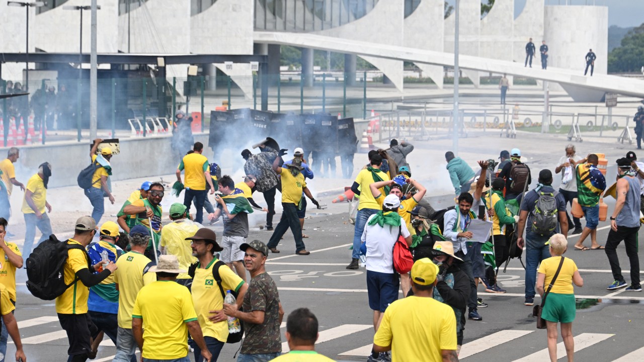 Supporters of Brazilian former President Jair Bolsonaro clash with the police during a demonstration outside the Planalto Palace in Brasilia on January 8, 2023. - Brazilian police used tear gas Sunday to repel hundreds of supporters of far-right ex-president Jair Bolsonaro after they stormed onto Congress grounds one week after President Luis Inacio Lula da Silva's inauguration, an AFP photographer witnessed. (Photo by EVARISTO SA / AFP)
