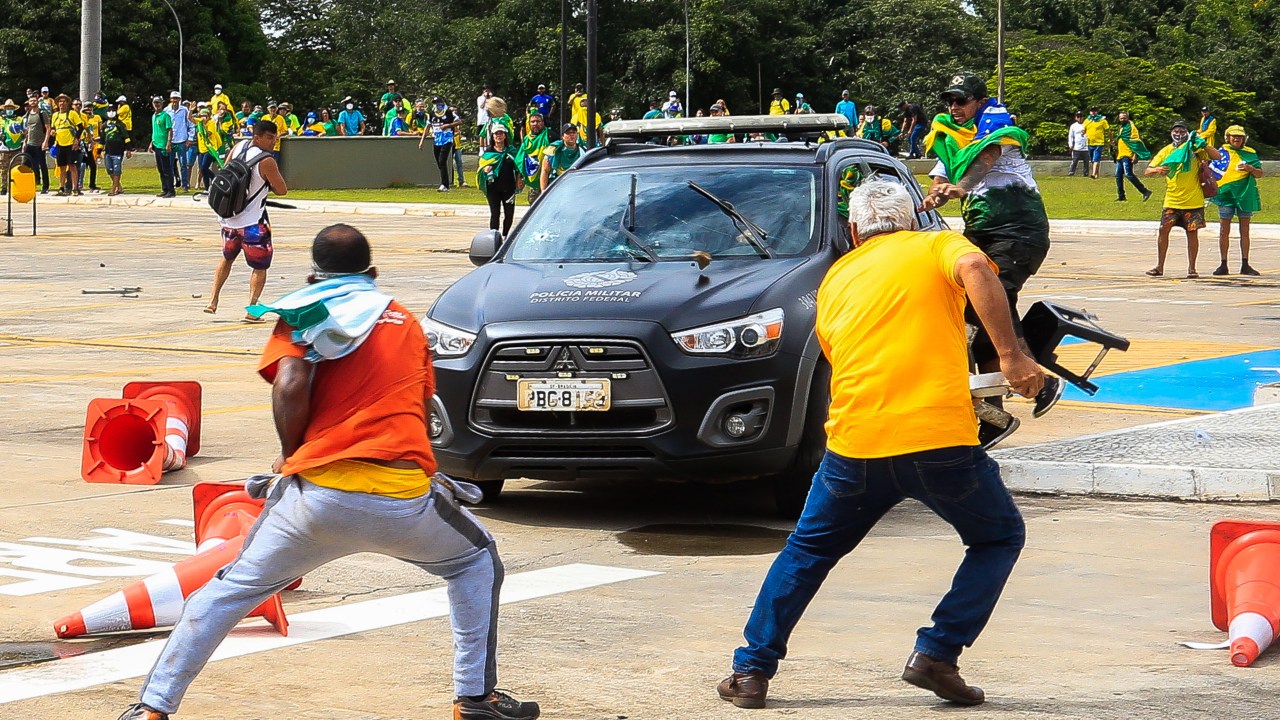 Supporters of Brazilian former President Jair Bolsonaro attack a vehicle of the Military Police during clashes outside Planalto Presidential Palace in Brasilia on January 8, 2023. - Hundreds of supporters of Brazil's far-right ex-president Jair Bolsonaro broke through police barricades and stormed into Congress, the presidential palace and the Supreme Court Sunday, in a dramatic protest against President Luiz Inacio Lula da Silva's inauguration last week. (Photo by Sergio Lima / AFP)