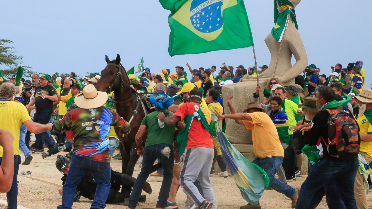 A Military Police officer falls from his horse during clashes with supporters of Brazilian former President Jair Bolsonaro after an invasion to Planalto Presidential Palace in Brasilia on January 8, 2023. - Hundreds of supporters of Brazil's far-right ex-president Jair Bolsonaro broke through police barricades and stormed into Congress, the presidential palace and the Supreme Court Sunday, in a dramatic protest against President Luiz Inacio Lula da Silva's inauguration last week. (Photo by Sergio Lima / AFP)