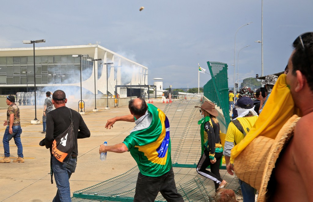 Supporters of Brazilian former President Jair Bolsonaro clash with riot police at Planalto Presidential Palace in Brasilia on January 8, 2023. - Hundreds of supporters of Brazil's far-right ex-president Jair Bolsonaro broke through police barricades and stormed into Congress, the presidential palace and the Supreme Court Sunday, in a dramatic protest against President Luiz Inacio Lula da Silva's inauguration last week. (Photo by Sergio Lima / AFP)