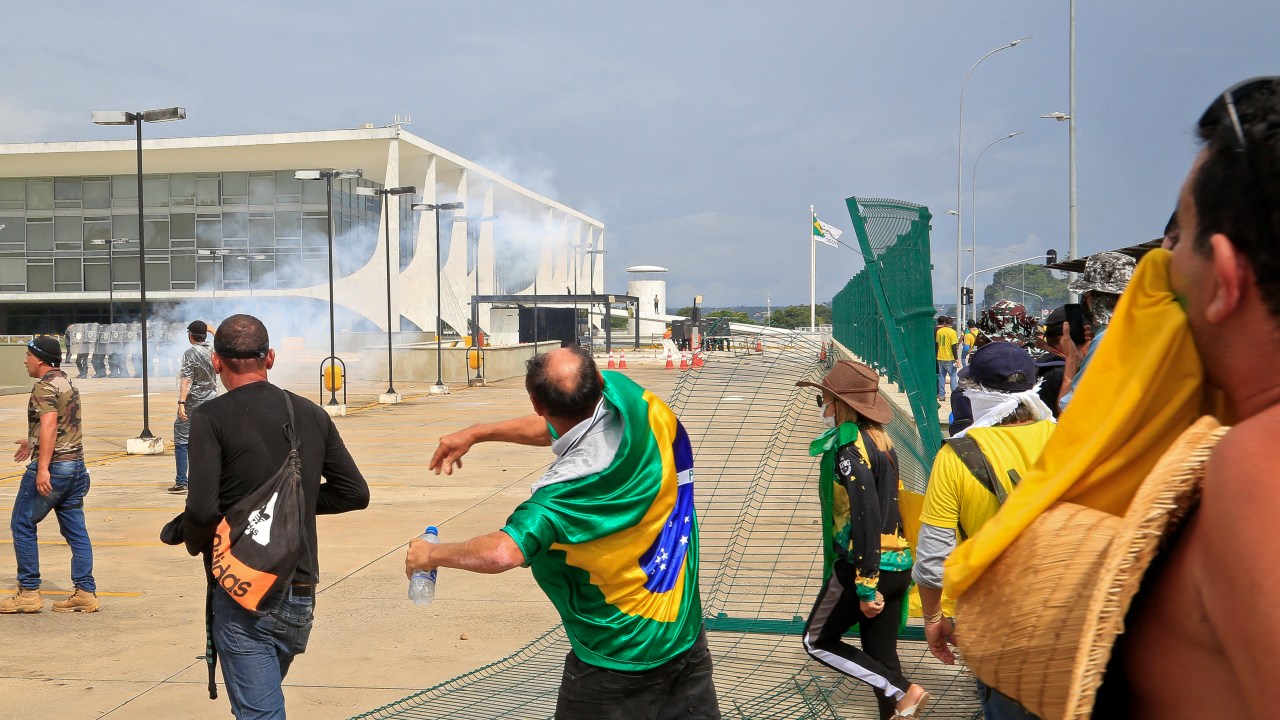 Supporters of Brazilian former President Jair Bolsonaro clash with riot police at Planalto Presidential Palace in Brasilia on January 8, 2023. - Hundreds of supporters of Brazil's far-right ex-president Jair Bolsonaro broke through police barricades and stormed into Congress, the presidential palace and the Supreme Court Sunday, in a dramatic protest against President Luiz Inacio Lula da Silva's inauguration last week. (Photo by Sergio Lima / AFP)