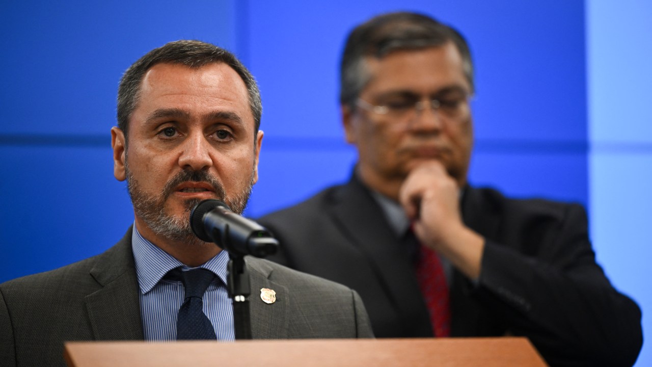 Brazilian Federal Police chief Andrei Passos Rodrigues speaks next to Brazilian Justice and Public Security Minister Flavio Dino during a press conference at the Justice Palace in Brasilia on January 9, 2023, a day after supporters of Brazil's far-right ex-president Jair Bolsonaro invaded the Congress, presidential palace and Supreme Court. - Brazilian security forces locked down the area around Congress, the presidential palace and the Supreme Court Monday, a day after supporters of ex-president Jair Bolsonaro stormed the seat of power in riots that triggered an international outcry. Hardline Bolsonaro supporters have been protesting outside army bases calling for a military intervention to stop Lula from taking power since his election win. (Photo by CARL DE SOUZA / AFP)