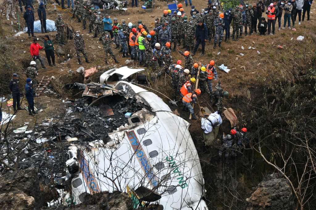 EDITORS NOTE: Graphic content / Rescuers pull the body of a victim who died in a Yeti Airlines plane crash in Pokhara on January 16, 2023. - Nepal observed a day of mourning on January 16 for the victims of the nation's deadliest aviation disaster in three decades, with 67 people confirmed killed in the plane crash. (Photo by PRAKASH MATHEMA / AFP)