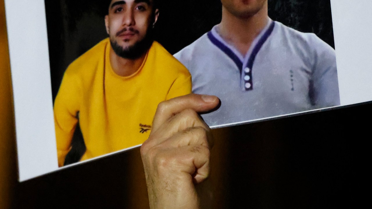 A protester holds a poster bearing portraits of Iranian protestors Mohammad Mehdi Karami (L) and Seyed Mohammad Hosseini who were executed in Iran earlier in January, during a gathering to display the slogan "Woman. Life. Freedom." on the Eiffel Tower, in a show of support to the Iranian people, in the wake of the death of young Iranian woman Masha Amini who died in the country's morality police custody, in Paris, on January 16, 2023. - Iran has been gripped by demonstrations since the September 16, 2022, death in custody of Masha Amini, a young Iranian Kurd who had been arrested for allegedly violating the country's strict dress code for women. (Photo by Ludovic MARIN / AFP)