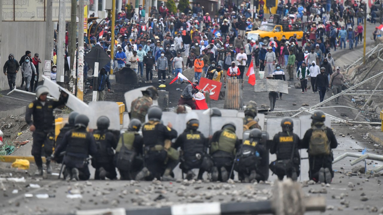 Demonstrators clash with riot police at the Añashuayco bridge in Arequipa, Peru, during a protest against the government of President Dina Boluarte and to demand her resignation on January 19, 2023. - After weeks of unrest, thousands of protesters were expected to descend on Peru's capital Lima, defying a state of emergency to express their anger with President Dina Boluarte, who called on the demonstrators to gather "peacefully and calmly". The South American country has been rocked by over five weeks of deadly protests since the ouster and arrest of her predecessor Pedro Castillo in early December. (Photo by Diego Ramos / AFP)