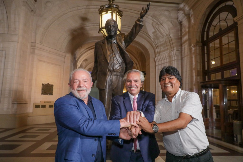 Handout picture released by the Argentinian presidency showing (L to R) Brazilian President Luiz Inacio Lula da Silva, Argentine President Alberto Fernandez, and Bolivian former President (2006-2019) Evo Morales shaking hands in front of a statue of late Argentine President (2003-2007) Nestor Kirchner during the concert of the Argentine-Brazilian brotherhood at Kirchner Cultural Center (CCK) in Buenos Aires on January 23, 2023. - Brazil's President Luiz Inacio Lula da Silva began his first international tour last Sunday with a visit to Argentina and Uruguay with the aim of restoring regional leadership to Brazil after the management of the far-right Jair Bolsonaro. (Photo by ESTEBAN COLLAZO / Argentinian Presidency / AFP) / RESTRICTED TO EDITORIAL USE - MANDATORY CREDIT "AFP PHOTO / ARGENTINIAN PRESIDENCY / ESTEBAN COLLAZO" - NO MARKETING NO ADVERTISING CAMPAIGNS - DISTRIBUTED AS A SERVICE TO CLIENTS