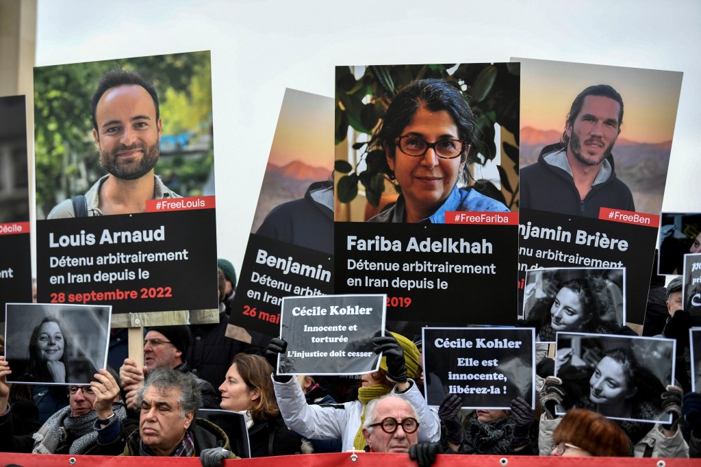 Demonstrators hold portraits of French detainees in Iran during a protest in their support at the "Esplanade du Trocadero" in Paris on January 28, 2023. - Paris said on January 25 that Foreign Minister Catherine Colonna in telephone talks with Iranian counterpart Hossein Amir-Abdollahian demanded the "immediate release of the seven French hostages arbitrarily detained" by Tehran. (Photo by STEPHANE DE SAKUTIN / AFP)