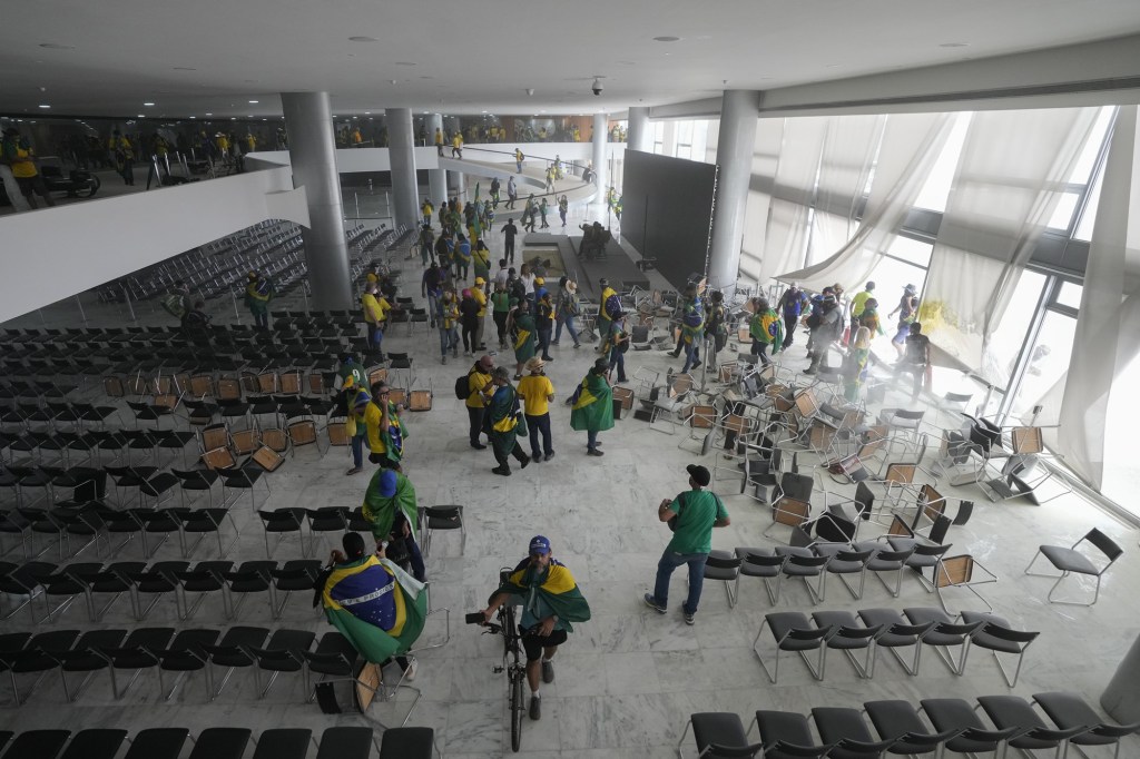 Protesters rifle through papers on a desk after storming the Planalto Palace(AP Photo/Eraldo Peres)