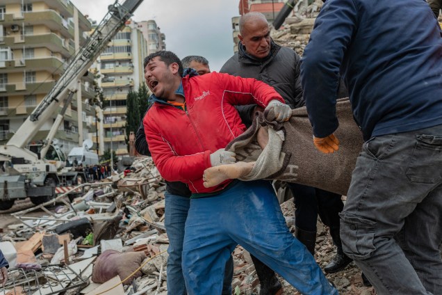 Um socorrista reage enquanto carrega um corpo encontrado nos escombros em Adana, na Síria -