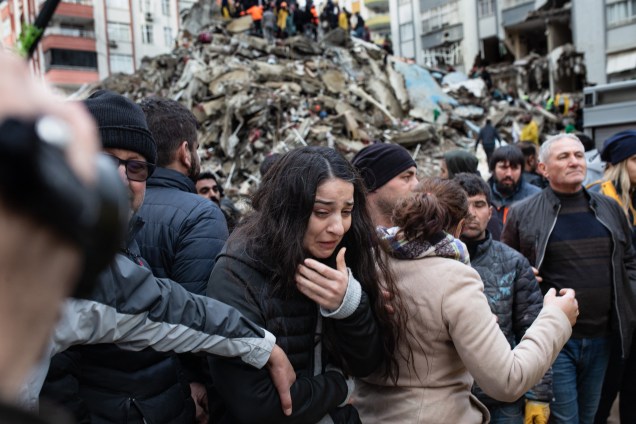 Uma mulher chora enquanto equipes de resgate procuram sobreviventes nos escombros de prédios desabados em Adana, na Síria -