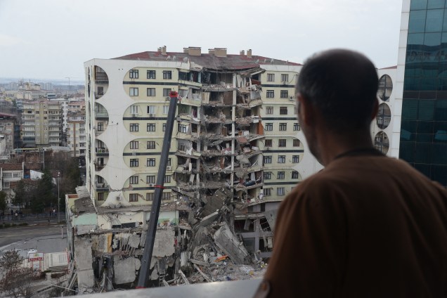 Um homem observa as operações de busca e resgate realizadas nos escombros de um prédio desabado, em Diyarbakir, na Síria -