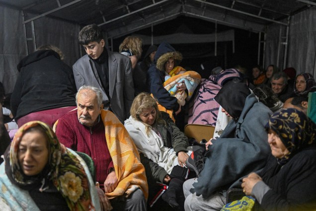 Sobreviventes do terremoto sentam-se abrigados em uma tenda em Hatay -