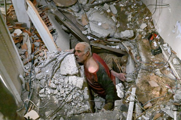 Um homem preso em escombros reage enquanto os destroços são removidos para trabalhar em seu resgate em Hatay -