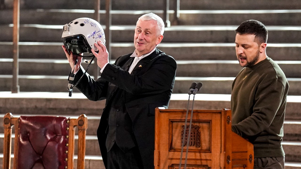 Speaker of the House of Commons, Sir Lindsay Hoyle (L), holds the helmet of one of the most successful Ukrainian pilots, inscribed with the words "We have freedom, give us wings to protect it", which was presented to him by Ukraine's President Volodymyr Zelensky during his address to British MPs in Westminster Hall, inside the Palace of Westminster, home to Britain's House of Commons and House of Lords in central London on February 8, 2023. - Ukraine's President Volodymyr Zelensky on Wednesday hailed Britain as "one of the first" countries to support Ukraine after Russia invaded, on his first visit to London since the war broke out nearly a year ago. (Photo by Stefan Rousseau / POOL / AFP)