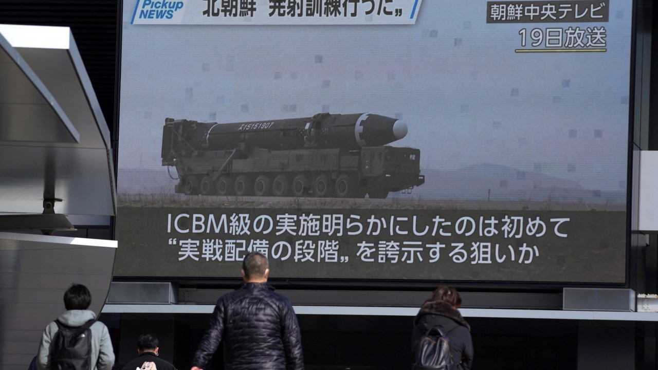 Pedestrians walk past a screen in Tokyo on February 20, 2023, displaying North Korea's missile launch footage broadcasted by Korean Central Television on February 19. (Photo by Kazuhiro NOGI / AFP)