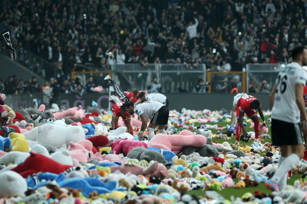 This handout photograph taken and released by Turkish agency DHA (Demiroren News Agency) on February 26, 2023 shows players collecting toys from the pitch as Besiktas fans throw toys onto the pitch during the Turkish Super League soccer match between Besiktas and Antalyaspor at the Vodafone stadium in Istanbul. - Besiktas supporters threw a massive number of soft toys to be donated to children affected by the powerful earthquake on Feb. 6 on southeast Turkey. (Photo by Handout / DHA (Demiroren News Agency) / AFP) / - Turkey OUT / RESTRICTED TO EDITORIAL USE - MANDATORY CREDIT "AFP PHOTO / DHA (DEMIROREN NEWS AGENCY) " - NO MARKETING NO ADVERTISING CAMPAIGNS - DISTRIBUTED AS A SERVICE TO CLIENTS