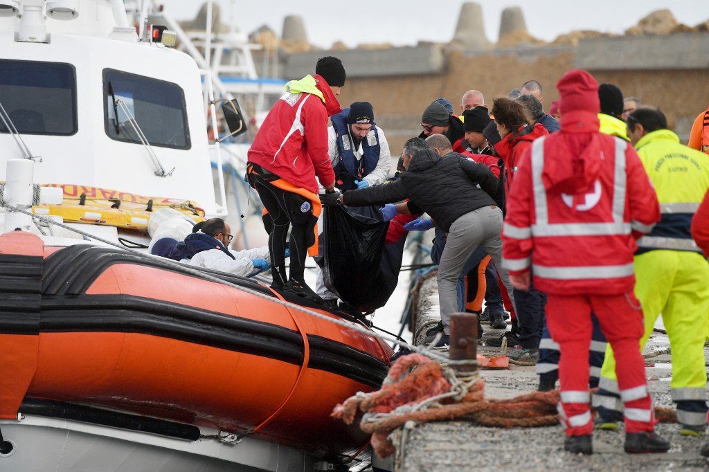 Italian Coast Guard officier carry the body of a deceased migrant in a bag, on February 27, 2023 in the port of Isola di Capo Rizzuto, south of Crotone, after a migrants' boat sank off Italy's southern Calabria region. - At least 59 migrants, including 11 children and a newborn baby, died after their overloaded boat sank early on February 26, 2023 in stormy seas off Italy's southern Calabria region, officials said. (Photo by Alessandro SERRANO / AFP)