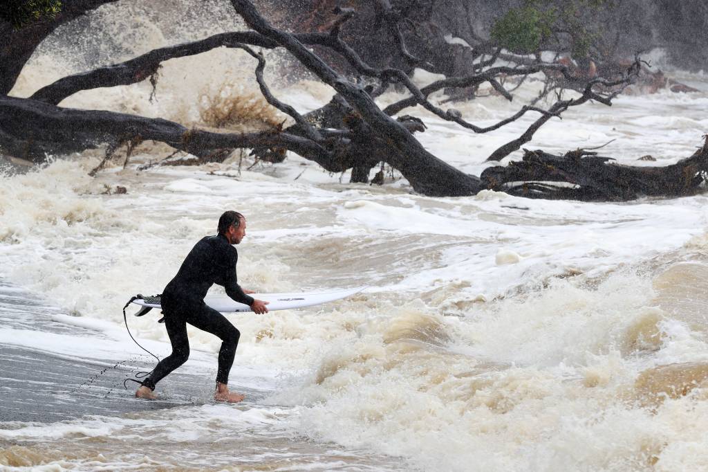 Um surfista se dirige para ondas grandes e mares agitados do ciclone Gabrielle na Reserva Marinha de Goat Island