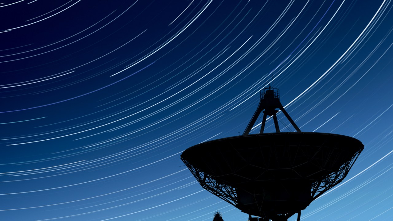 large radio telescopes in silhouette at night with long exposure starry sky, vertical frame (XXL)