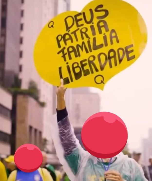 Frame da propaganda eleitoral de Bolsonaro, em 2022, filmada durante os atos de 7 de Setembro, em que manifestante segura cartaz com referências ao QAnon --
