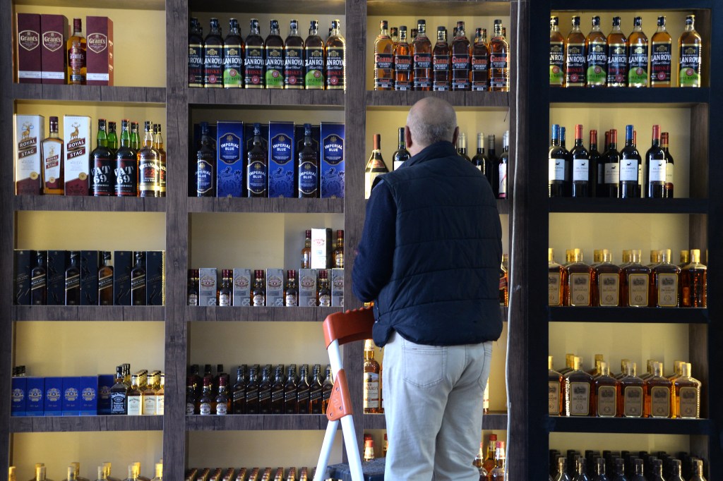 A shopworker arranges whisky bottles on a shelf at a liquor shop in Mosul on February 23, 2023. - Iraq's customs authorities announced on March 4, 2023, the official ban on the import, sale and manufacture of alcoholic beverages. (Photo by Zaid AL-OBEIDI / AFP)