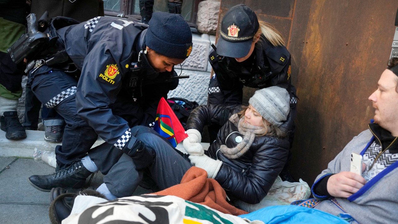 Policewomen carry away Swedish climate activist Greta Thunberg (C) as she demonstrated with other campaigners outside the Ministry of Finance and several other ministries on March 1, 2023 in Oslo, Norway, to protest against wind turbines built on land traditionally used to herd reindeer. - Thunberg and dozens of indigenous Sami activists were forcibly removed by police as they continued to block access to Norwegian ministries protesting against the operation of contested wind turbines in the Fosen region of western Norway, more than a year after a landmark ruling by the Norwegian Supreme Court. (Photo by Javad Parsa / NTB / AFP) / Norway OUT