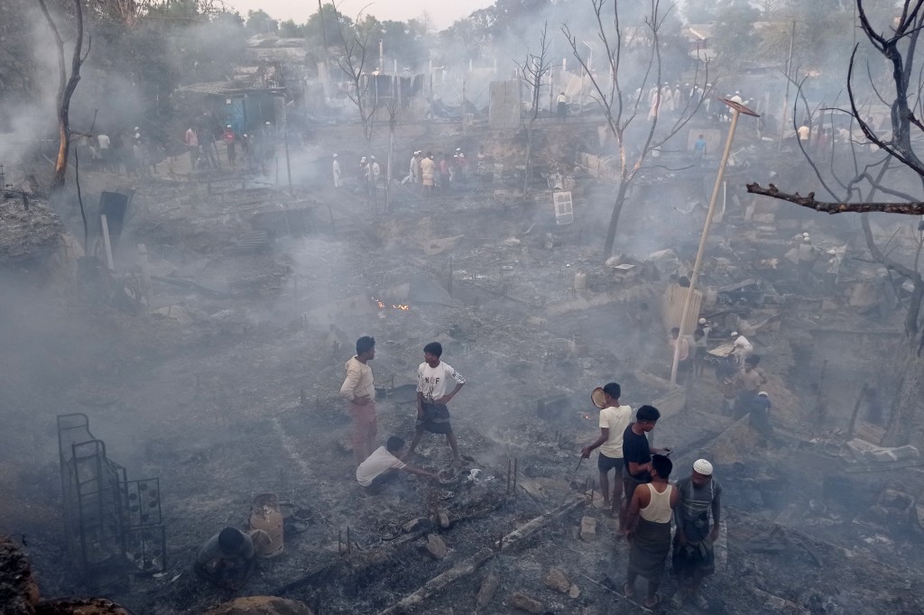Rohingya refugees search for their belongings after a fire broke out in Balukhali refugee camp in Ukhia on March 5, 2023. - A major fire in a Rohingya refugee camp in Bangladesh's southeast Sunday burnt 2,000 shelters, leaving around 12,000 people homeless, an official said. (Photo by Tanbir Miraz / AFP)