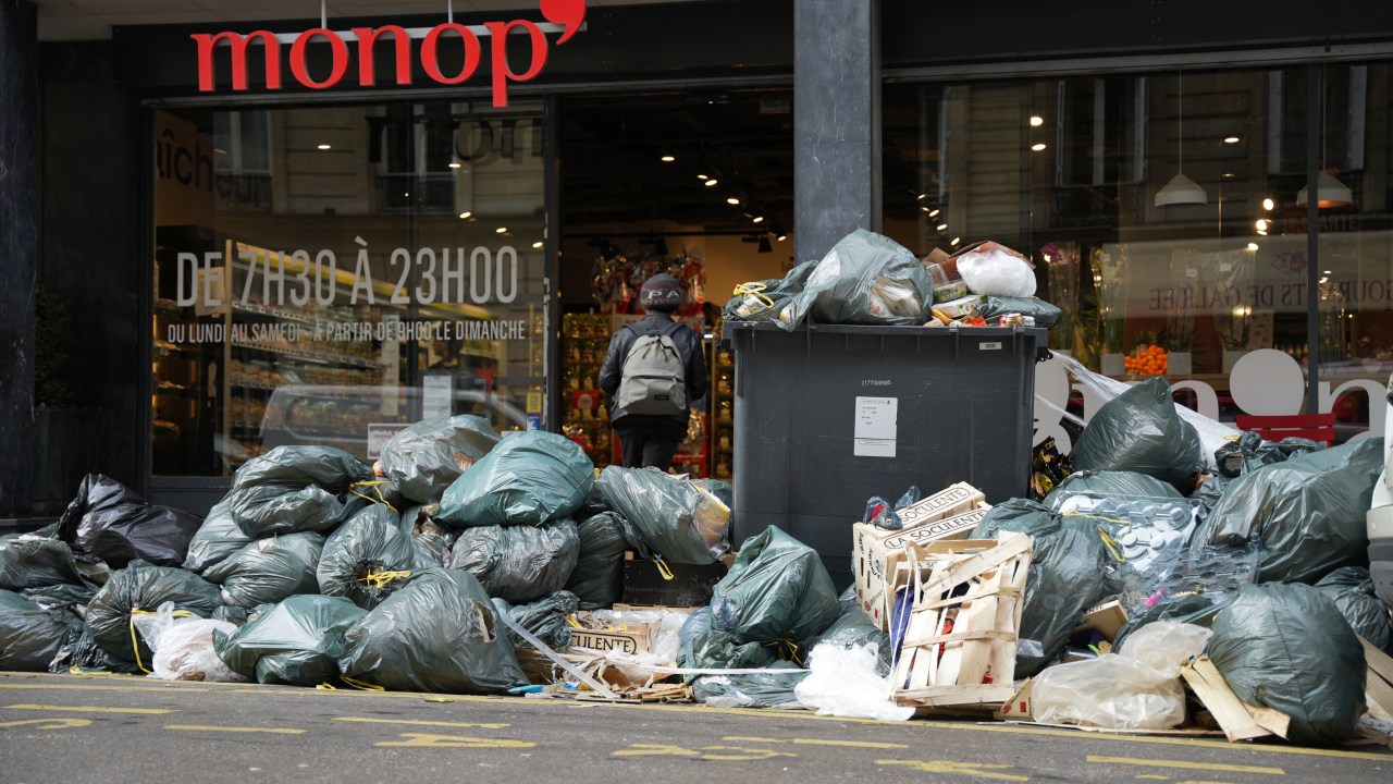 Piles of garbage accumulates outside a super market in Paris on March 14, 2023, since collectors went on strike against the French government's proposed pensions reform. - Thousands of tonnes of garbage have piled up on streets across the French capital after a week of strike action by dustbin collectors against government pension reforms, city hall said on March 12, 2023. (Photo by Zakaria ABDELKAFI / AFP)