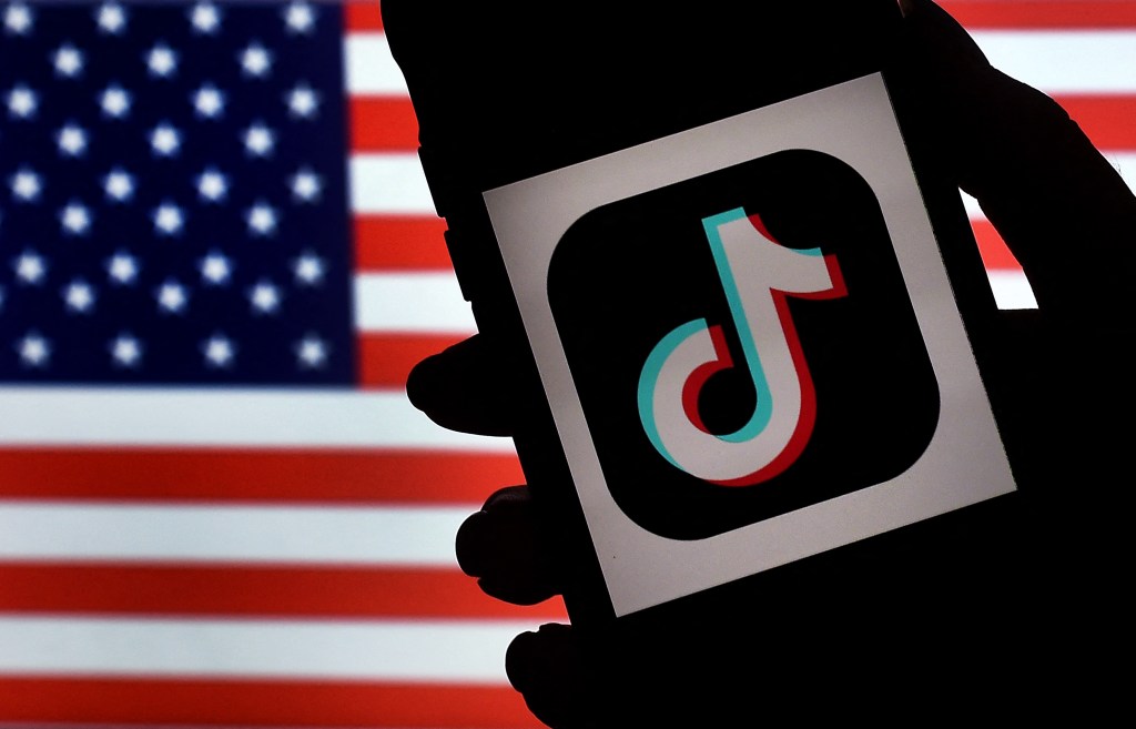 (FILES) In this file photo illustration taken on August 3, 2020, the social media application logo, TikTok, is displayed on the screen of an iPhone on a US flag background in Arlington, Virginia. - The US government has told China-based ByteDance to sell its shares in the blockbuster TikTok app or face a national ban, the Wall Street Journal reported on March 15, 2023. (Photo by Olivier DOULIERY / AFP)