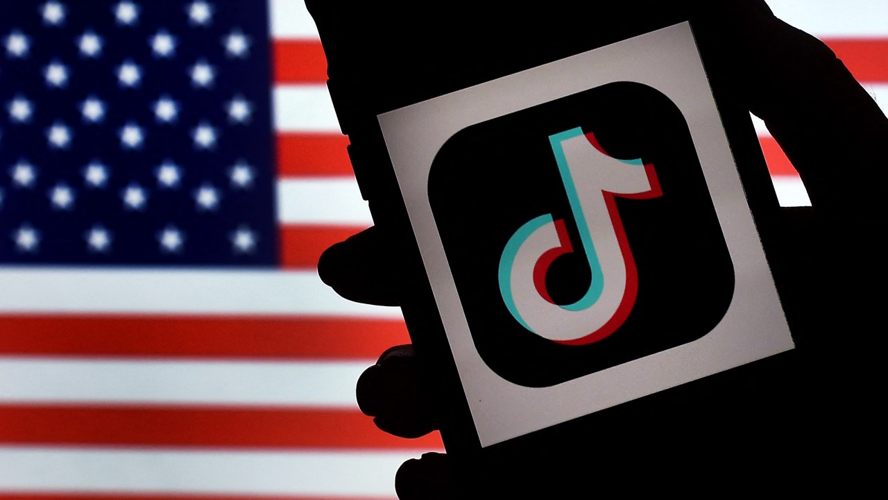 (FILES) In this file photo illustration taken on August 3, 2020, the social media application logo, TikTok, is displayed on the screen of an iPhone on a US flag background in Arlington, Virginia. - The US government has told China-based ByteDance to sell its shares in the blockbuster TikTok app or face a national ban, the Wall Street Journal reported on March 15, 2023. (Photo by Olivier DOULIERY / AFP)