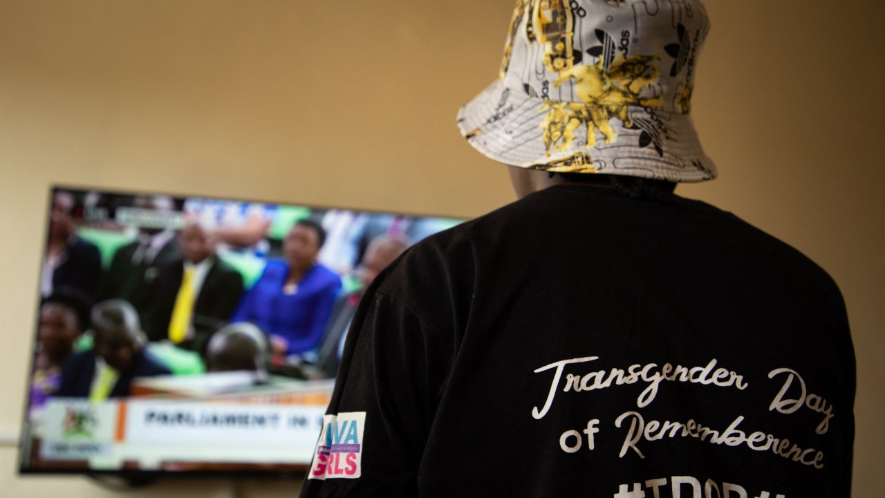 A Ugandan transgender woman who was recently attacked and currently being sheltered watches a TV screen showing the live broadcast of the session from the Parliament for the anti-gay bill, at a local charity supporting the LGBTQ Community near Kampala on March 21, 2023. - Uganda's parliament was due to vote on March 21, 2023 on anti-gay legislation which proposes tough new penalties for same-sex relations in a country where homosexuality is already illegal.Under the proposed law, anyone in the conservative East African nation who engages in same-sex activity or who identifies publicly as LGBTQ could face up to 10 years in prison. (Photo by STUART TIBAWESWA / AFP)