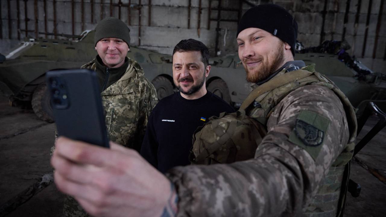 This handout picture taken and released by the Ukrainian Presidential press service on March 22, 2023 shows President Volodymyr Zelensky (C) taking a selfie with servicemen after meeting them in a warehouse and handing out awards, near Bakhmut. - President Volodymyr Zelensky visited military positions near the frontline town of Bakhmut in eastern Ukraine, the scene of the longest and bloodiest battle since Russia's invasion, he said. (Photo by Handout / UKRAINIAN PRESIDENTIAL PRESS SERVICE / AFP) / RESTRICTED TO EDITORIAL USE - MANDATORY CREDIT "AFP PHOTO / HANDOUT / UKRAINIAN PRESIDENTIAL PRESS SERVICE " - NO MARKETING NO ADVERTISING CAMPAIGNS - DISTRIBUTED AS A SERVICE TO CLIENTS