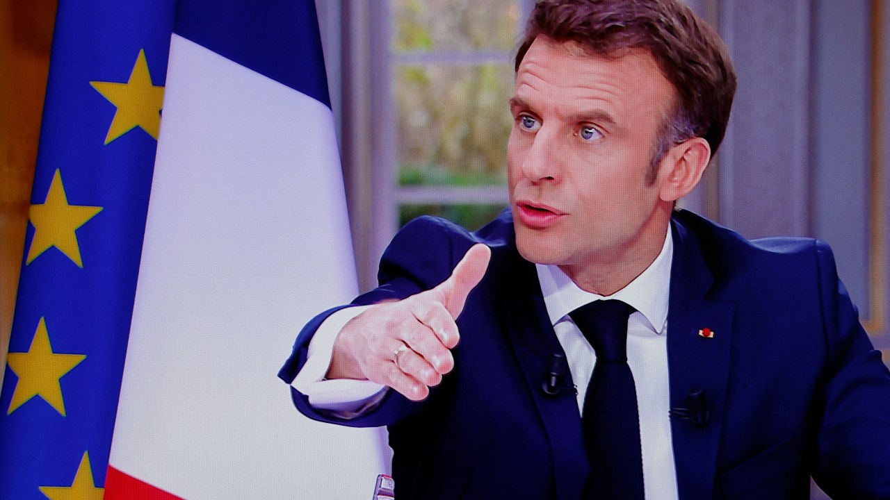 French President Emmanuel Macron is seen on screen as he speaks during a TV interview from the Elysee Palace, in Paris, on March 22, 2023. - French President is to make on March 22, 2023 his first public comments on the crisis sparked by his government forcing through a pensions overhaul, which has sparked violent protests and questions over his ability to bring about further change. (Photo by Ludovic MARIN / AFP)